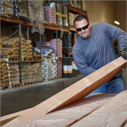 A Ganahl employee picking up a wooden beam.