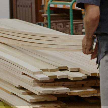 A person picking up the pieces of lumber they need off of a stack. 