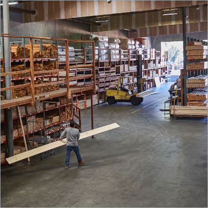 A Ganahl employee carrying a large piece of lumber through the covered lumberyard.