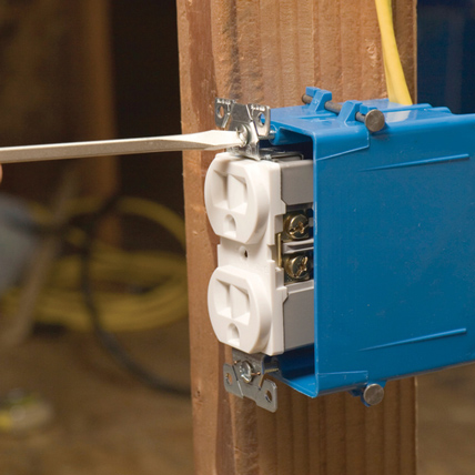A flathead screwdriver being used to screw in an electrical socket.